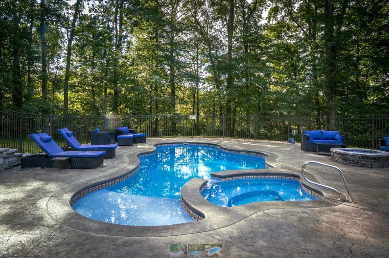 A large swimming pool surrounded by trees and chairs in a backyard.