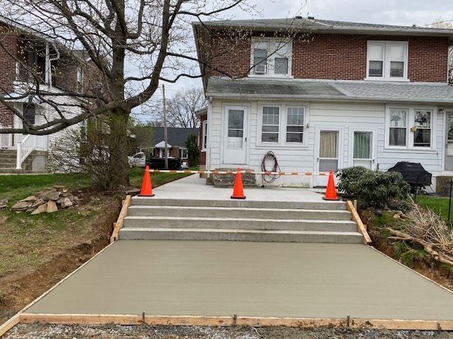 A concrete walkway is being built in front of a house.