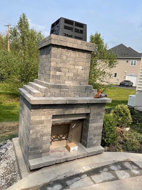 A brick fireplace is being built in the backyard of a house.