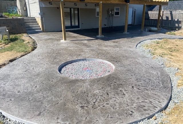 A concrete patio with a fire pit in the middle of it.