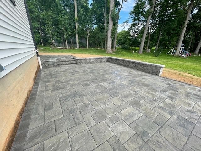 A patio with steps leading up to it is next to a house.