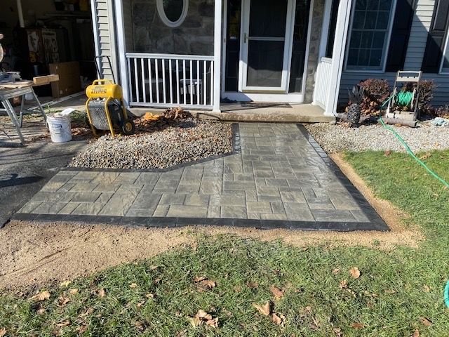 A patio is being built in front of a screened in porch.