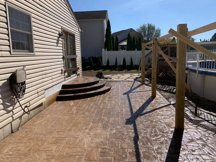 A patio with stairs and a wooden fence in front of a house.