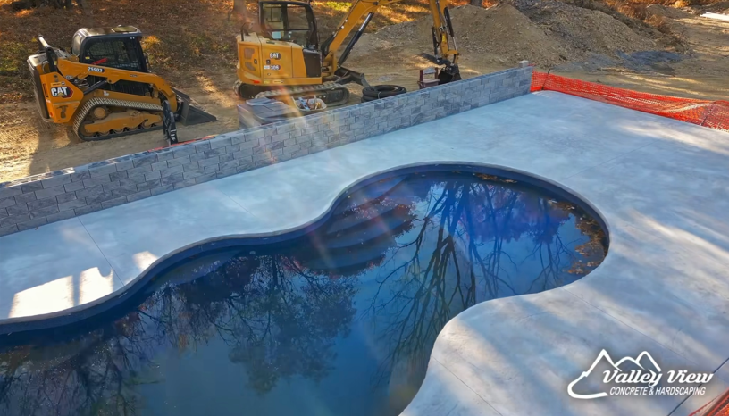A swimming pool is being built with a bulldozer in the background.