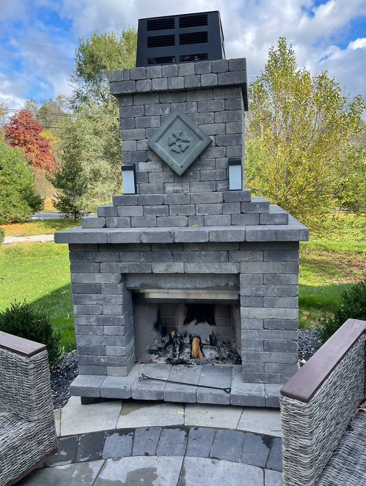 A large brick fireplace is sitting in the middle of a lush green field.