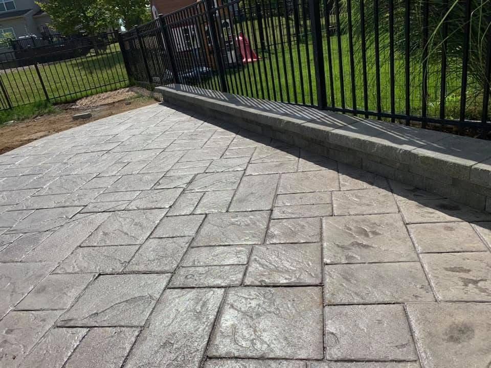 A concrete patio with a metal fence in the background.