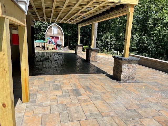 A patio with a covered area and a barn in the background.