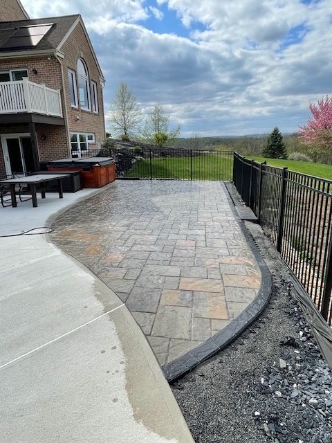 A patio with a fence and a house in the background.