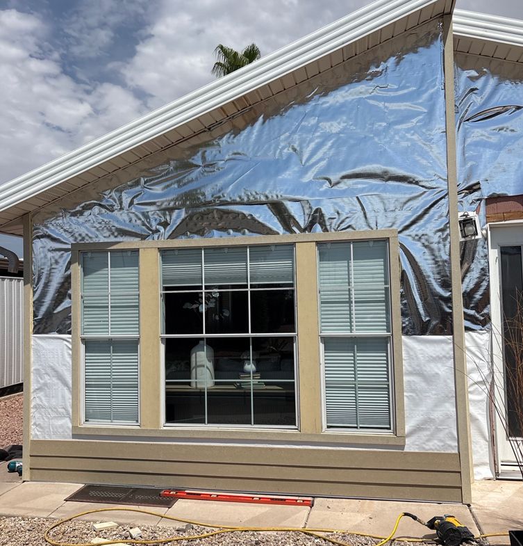 A house exterior with silver reflective insulation installed on a gable wall, around windows.