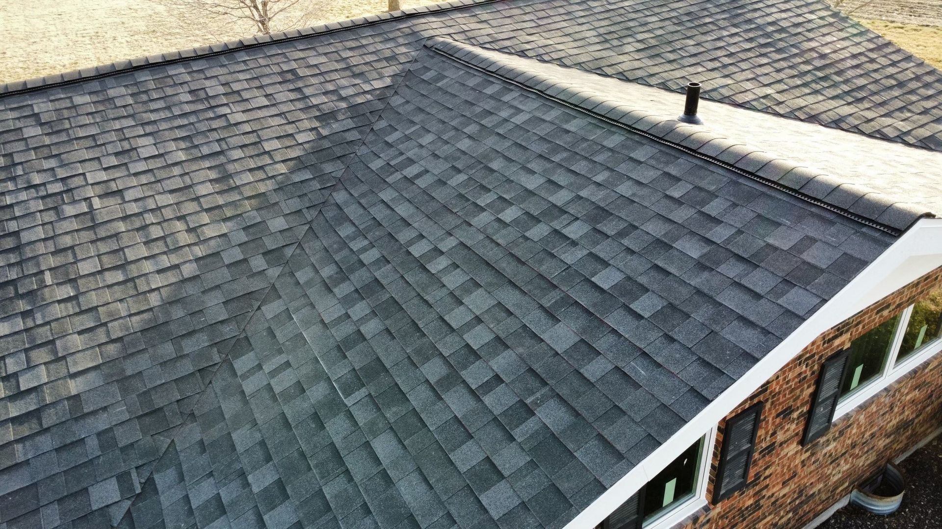 Aerial view of a roof on a brick house with a dark shingle roof.