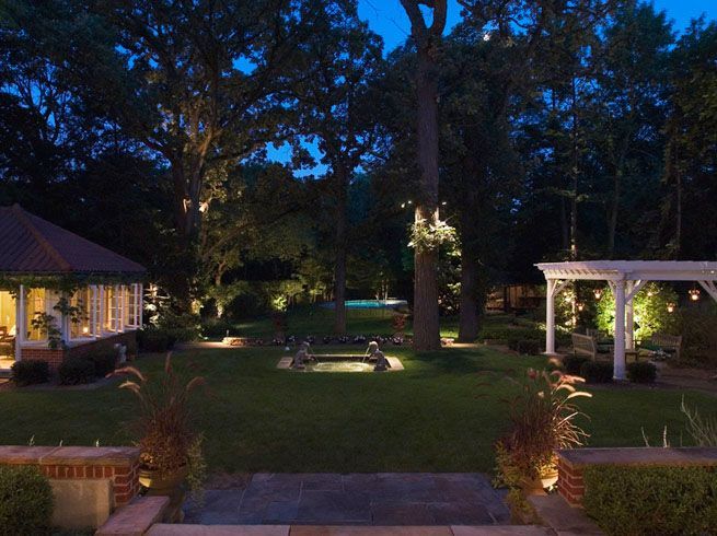 A large backyard with a gazebo and a pool at night.