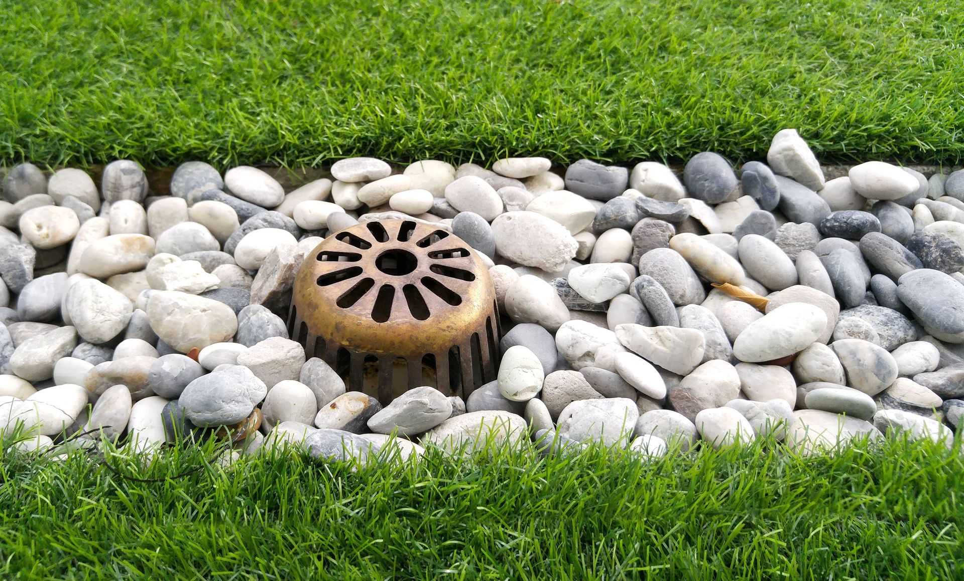 A drain is sitting in the middle of a pile of rocks.