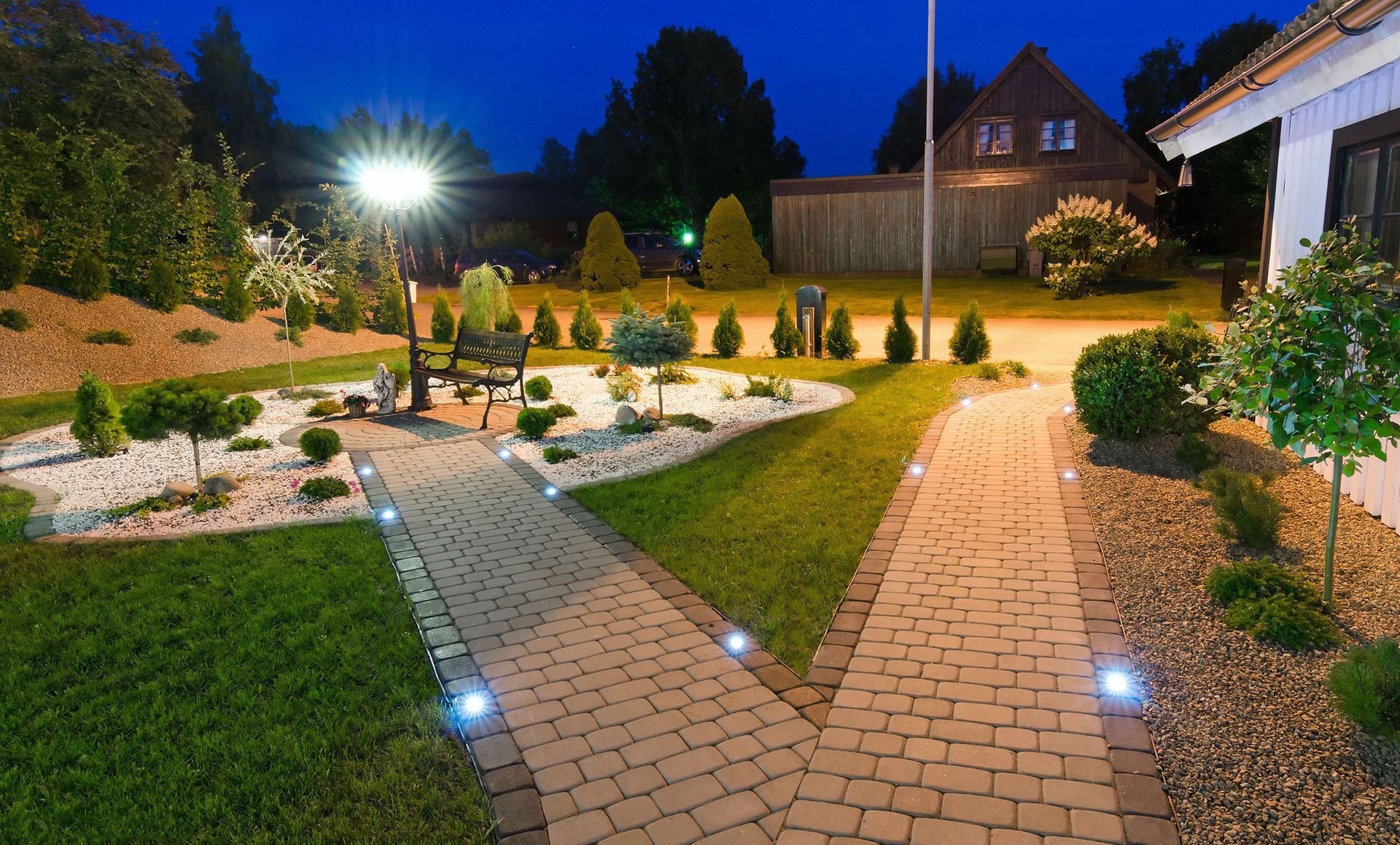 A brick walkway leading to a house at night
