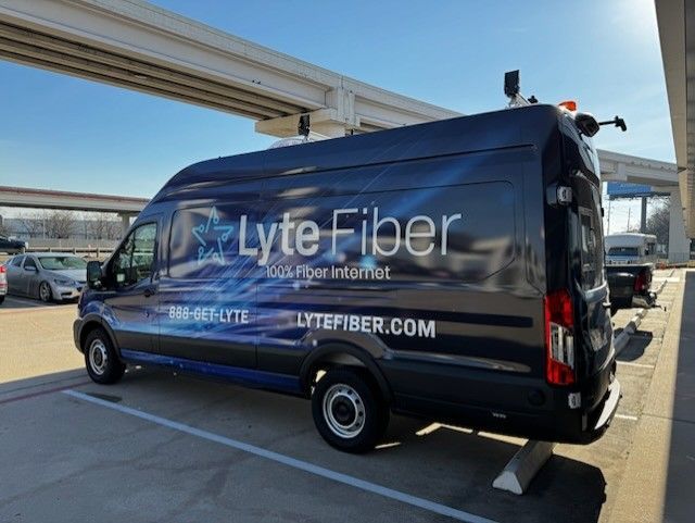 Dark blue Lyte Fiber van parked outdoors; website and phone number are visible.