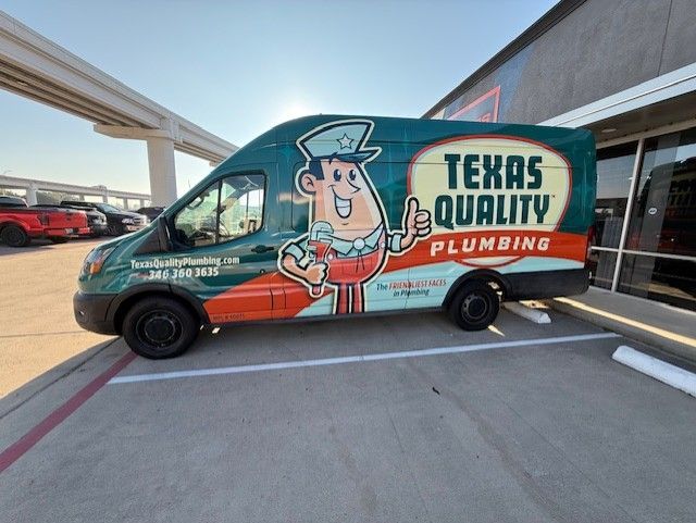 Texas Quality Plumbing van with a smiling cartoon plumber on the side. Parked outside a building.