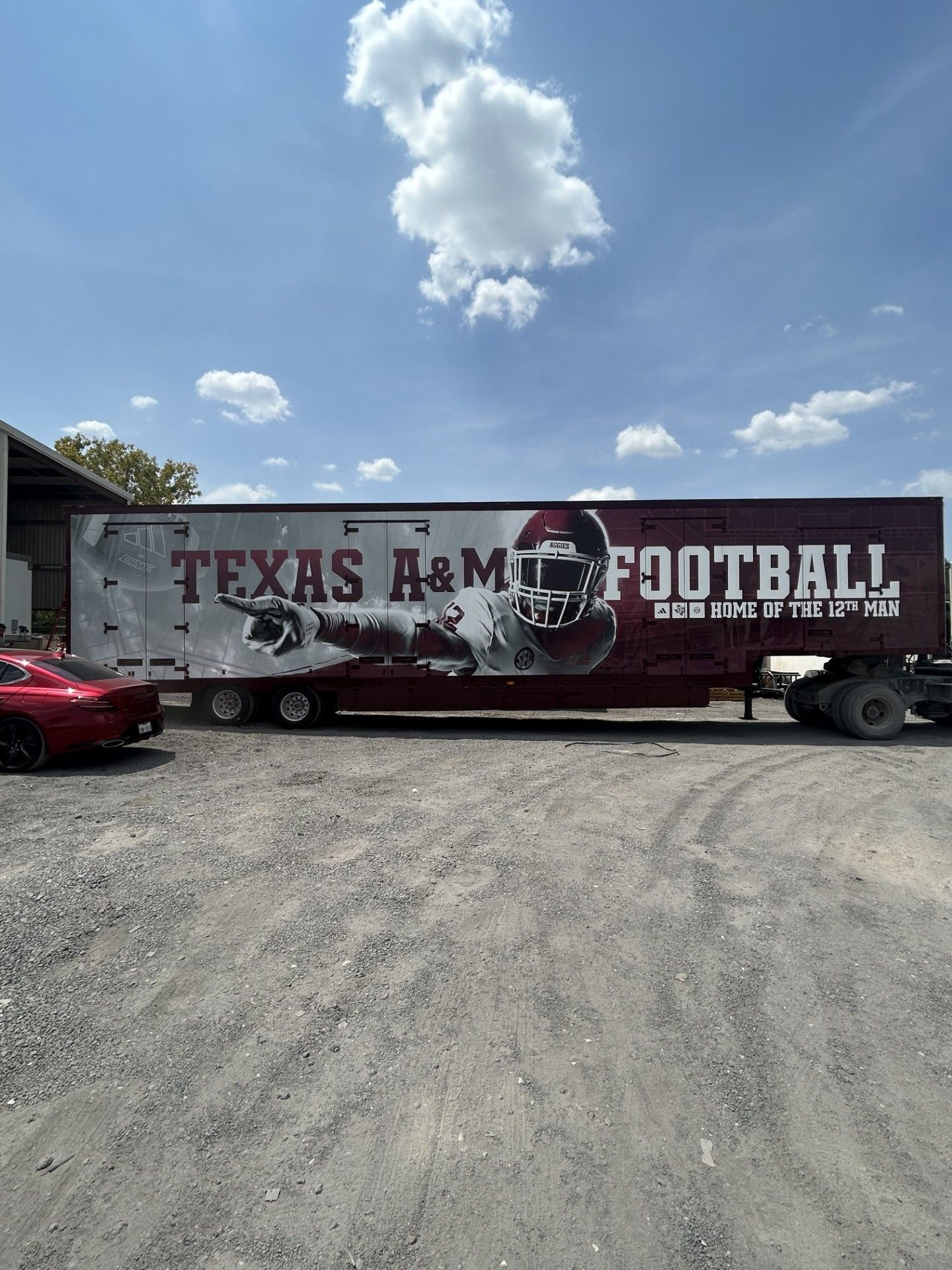 Texas A&M football trailer with logo on the side; burgundy and white; parked outdoors.