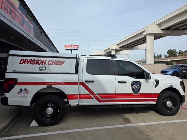 White Division Chief pickup truck with red stripes and logos parked near a building under a bridge.