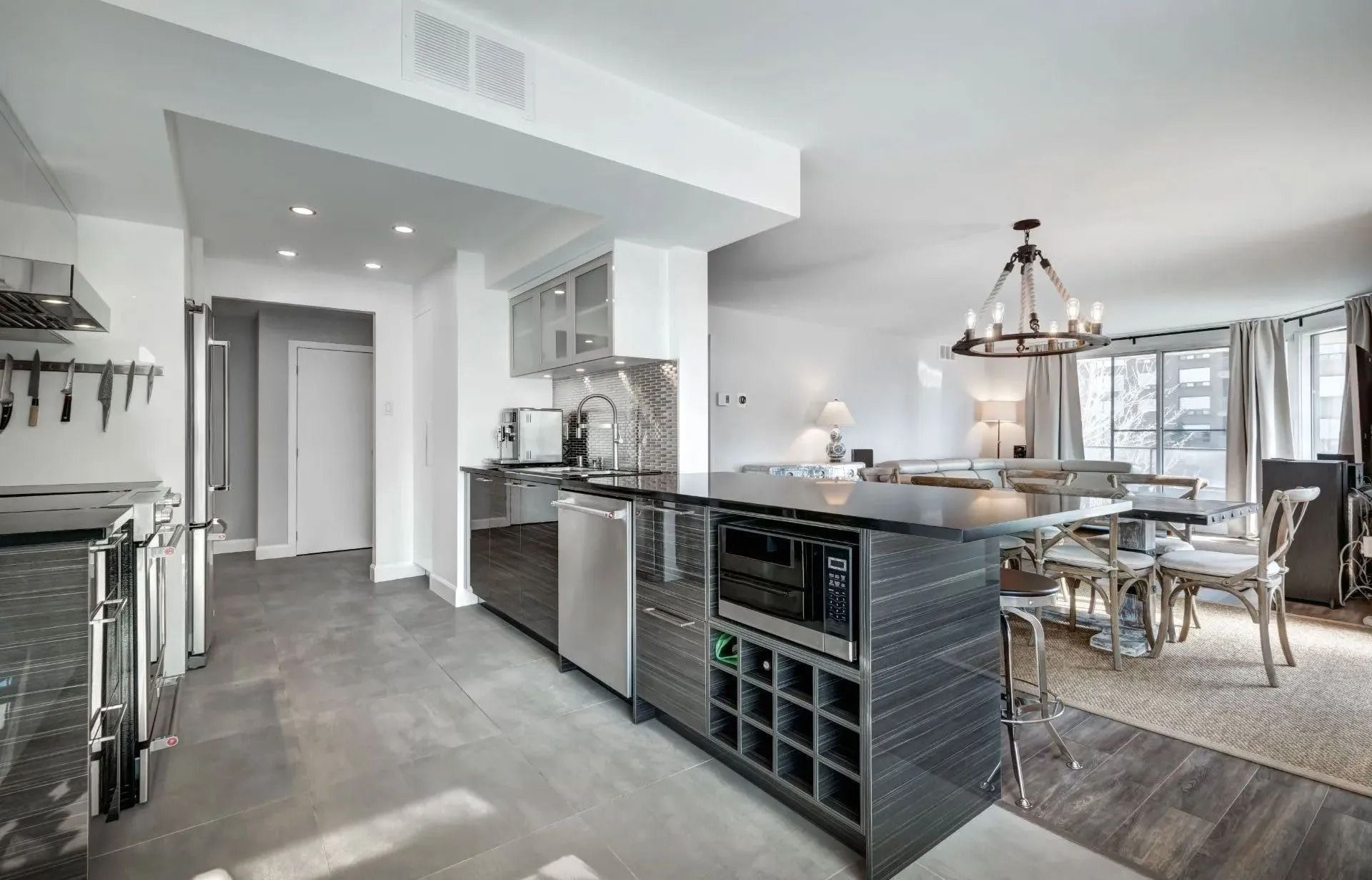 Modern open-plan kitchen and dining area with stainless steel appliances, dark countertops, and a dining table.