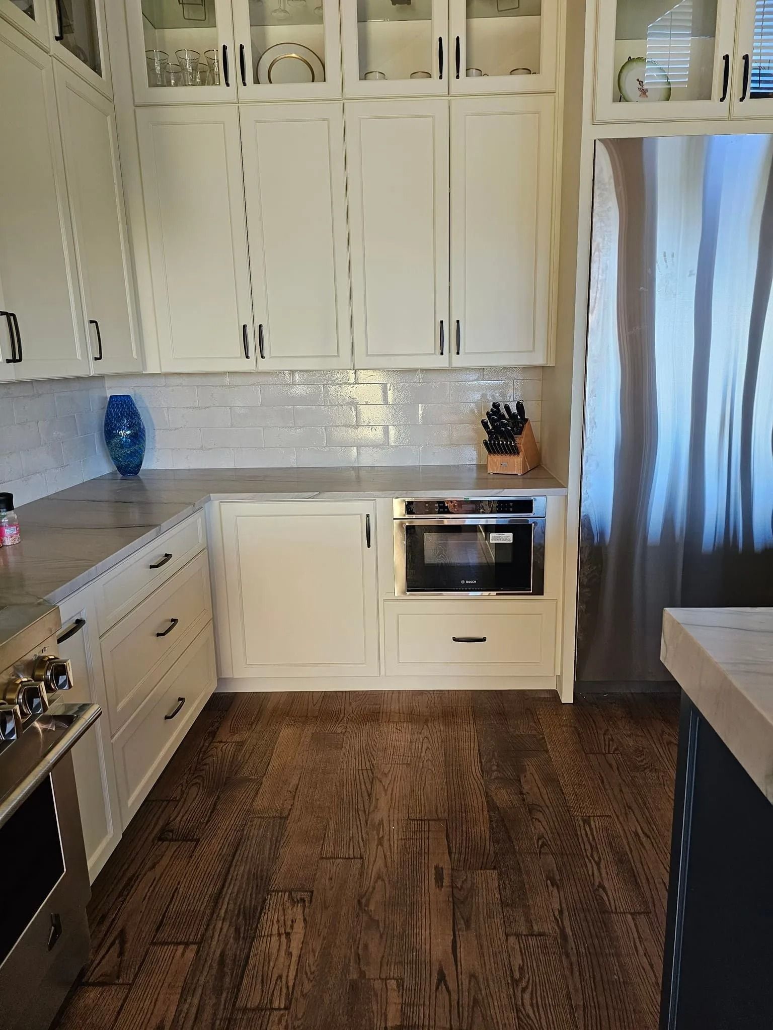 White kitchen with a built-in microwave, upper cabinets, and dark hardwood floors.