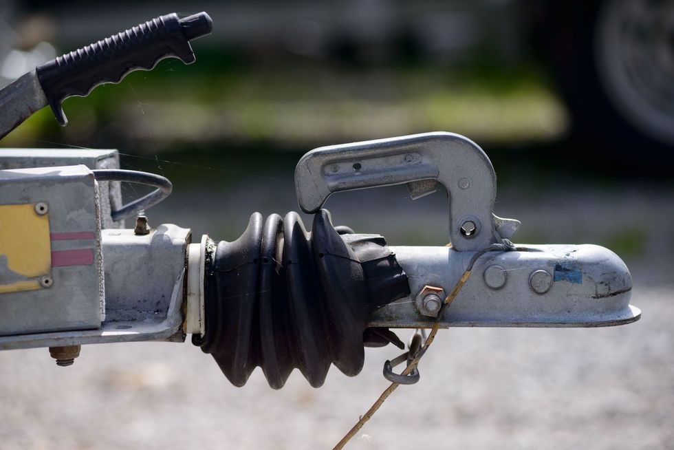 Close-up of a silver trailer hitch coupler with black rubber boot on a vehicle tongue.