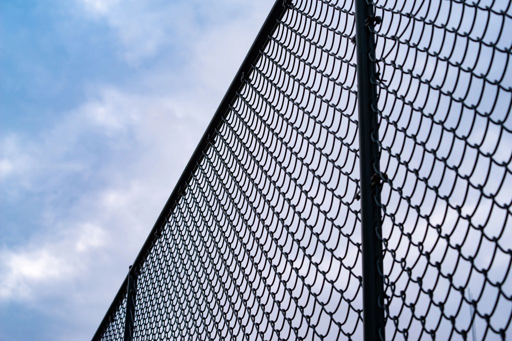 Chain-link fence against a cloudy sky.