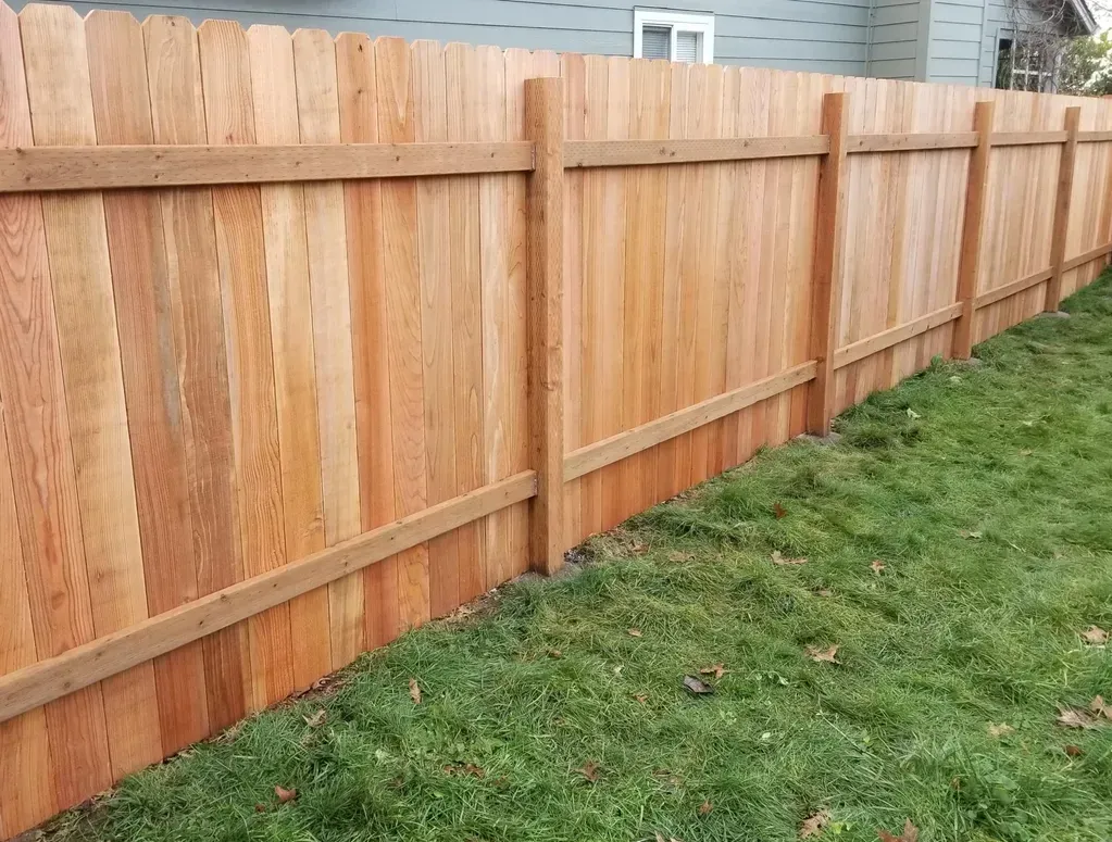 Wooden fence with natural wood grain in a grassy yard.