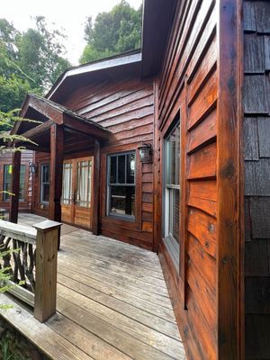 Wooden cabin exterior with a porch, brown siding and cedar shake siding.