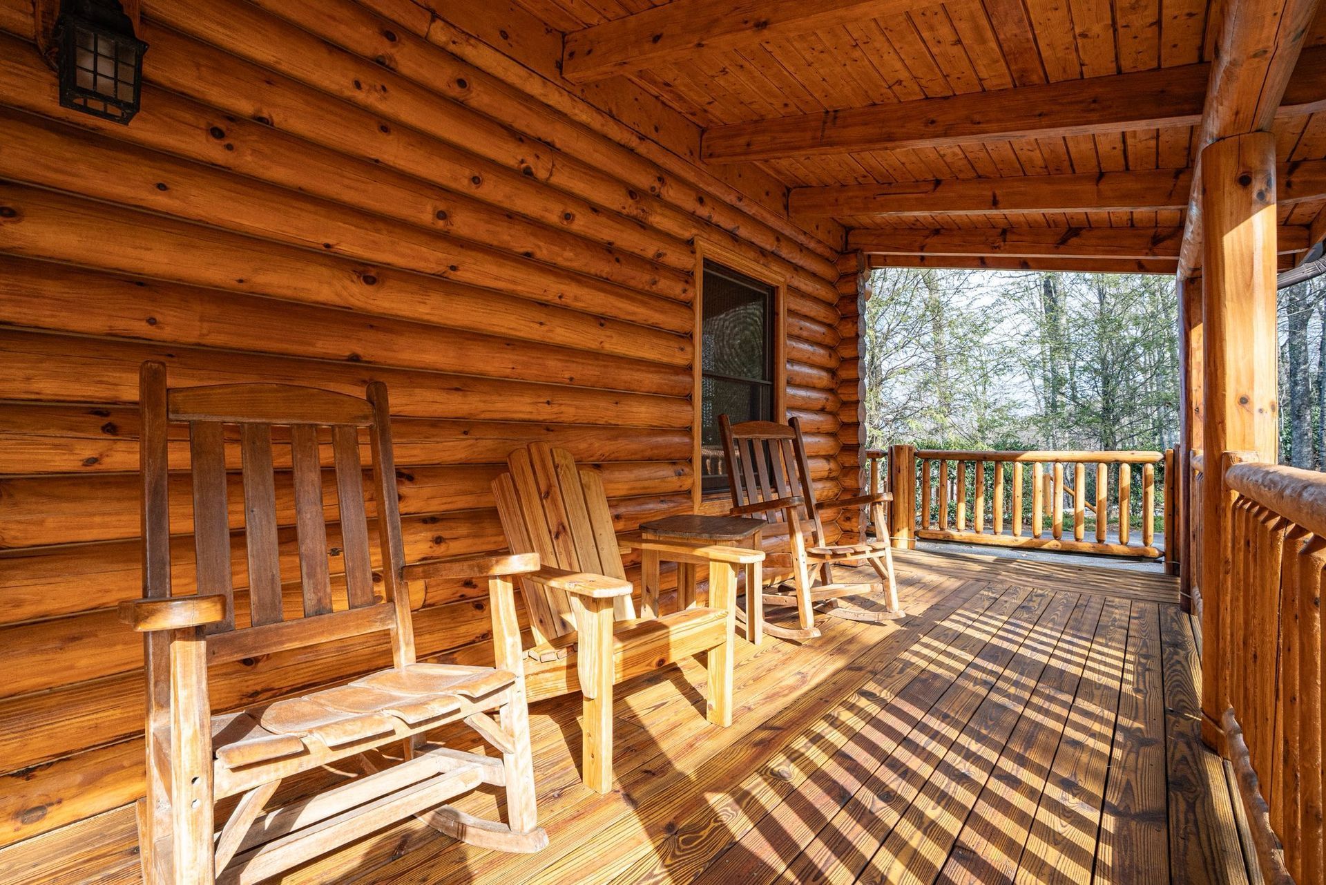 Wooden porch with rocking chairs overlooking trees; warm sunlight.