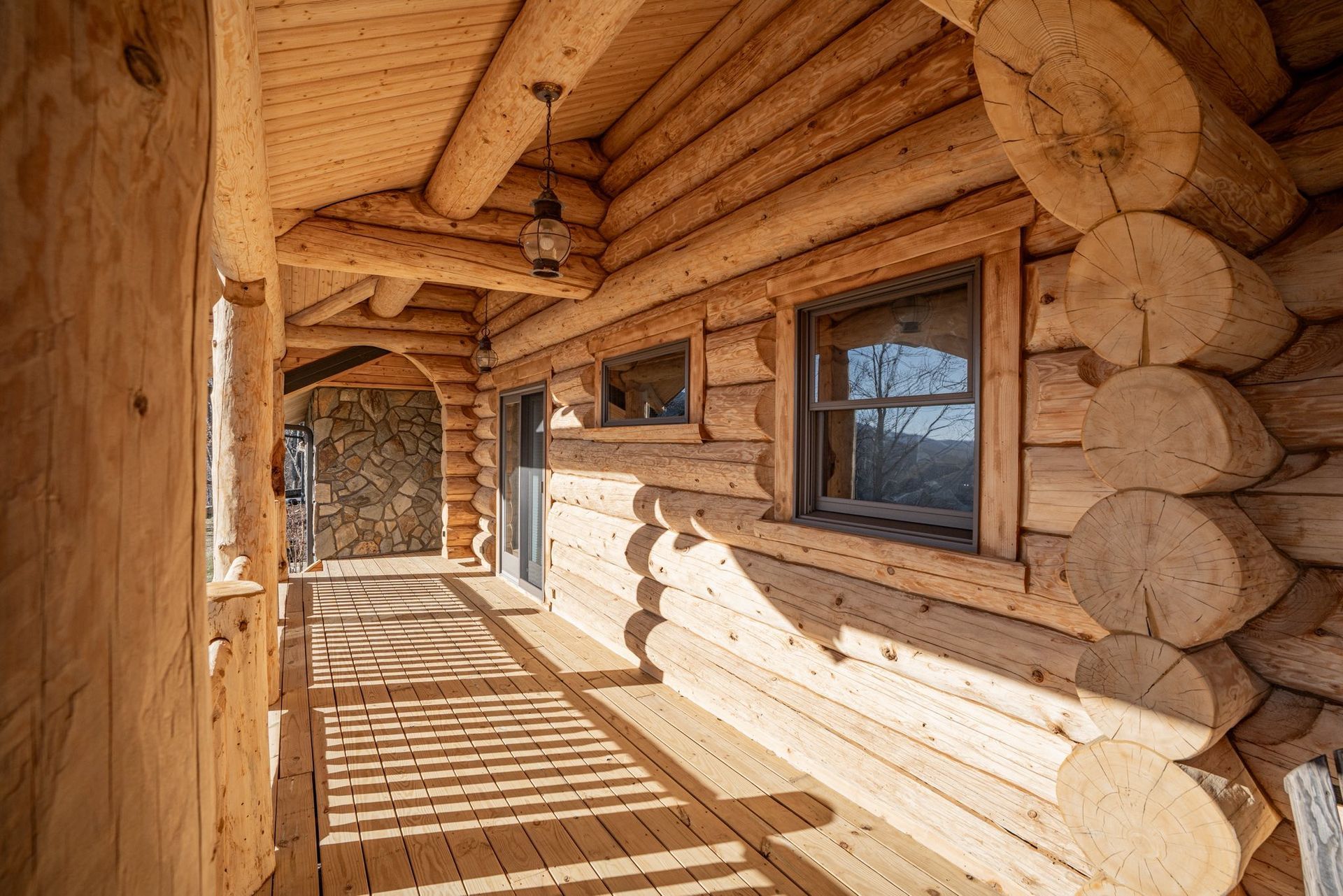 Wooden cabin porch with log walls and a window.