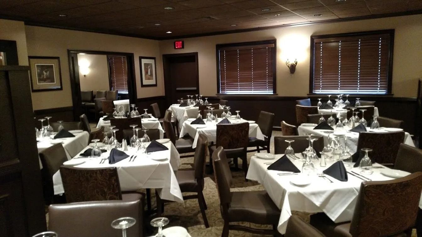Elegant dining room with white tablecloths, set tables, and dark wood accents.