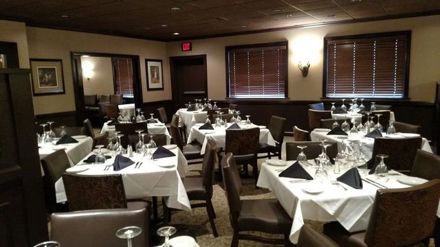 Elegant dining room with white tablecloths, set tables, and dark wood accents.