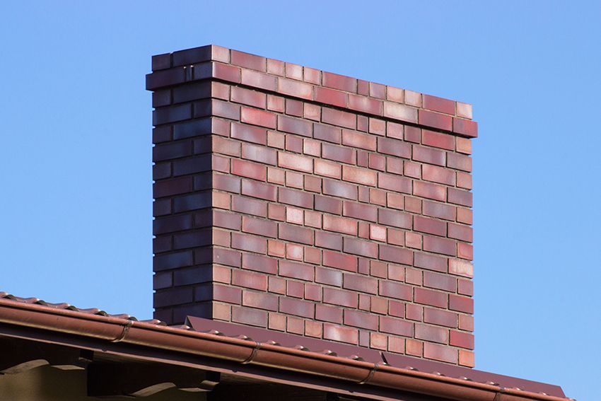 Several white service vans parked in front of a building with a company sign, under a clear blue sky.