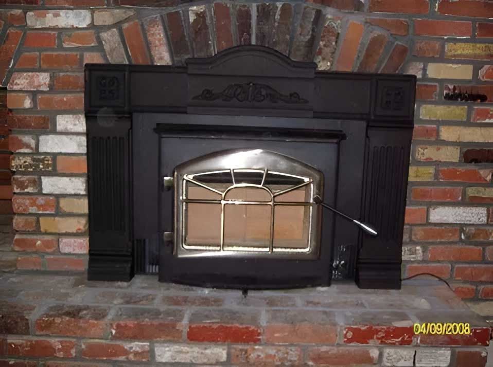 Black wood stove inset into a brick fireplace.