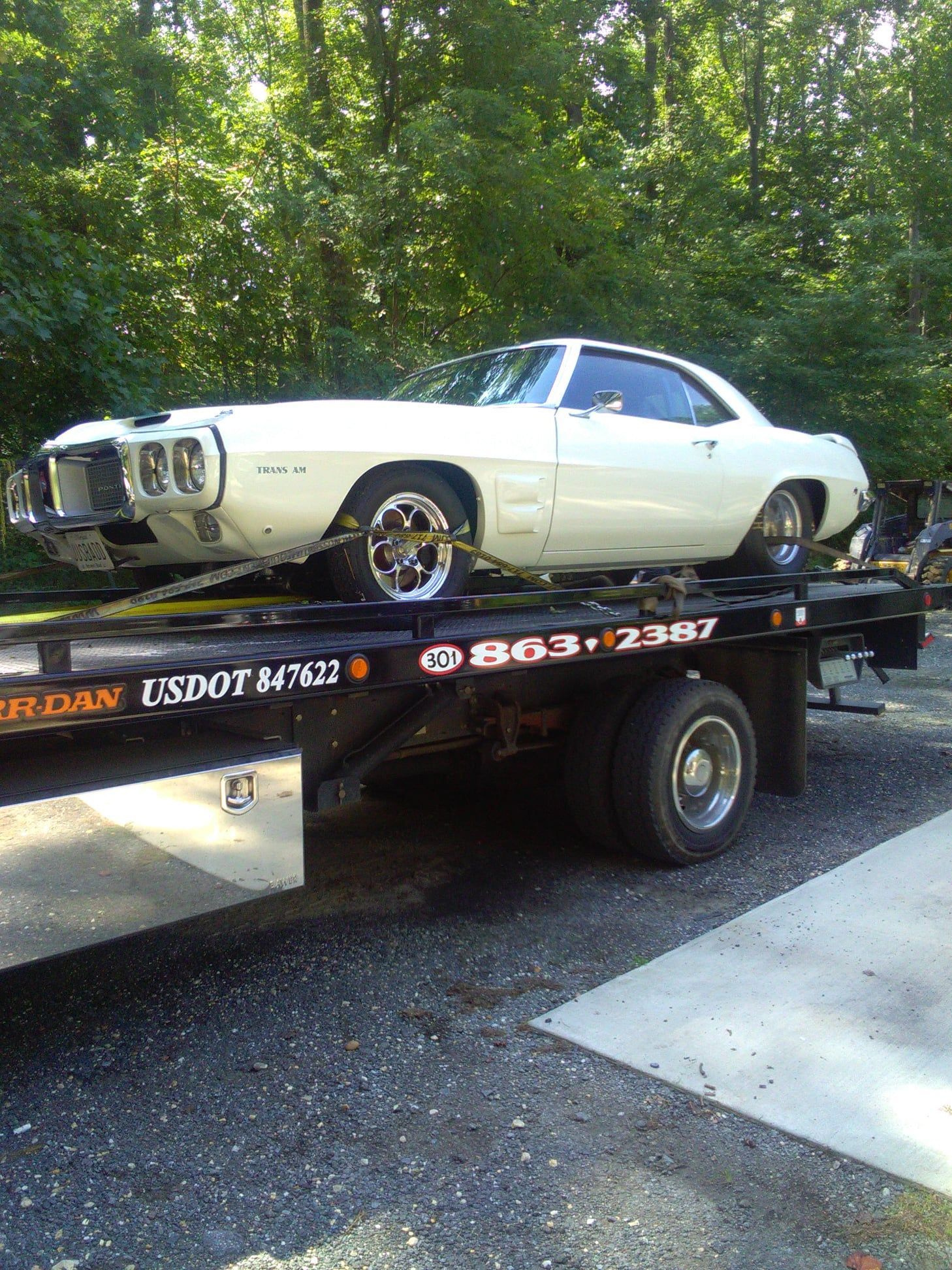 A white car is sitting on top of a tow truck.