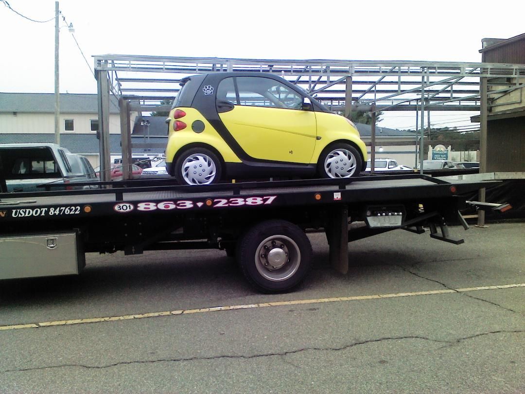 A yellow car is sitting on top of a tow truck
