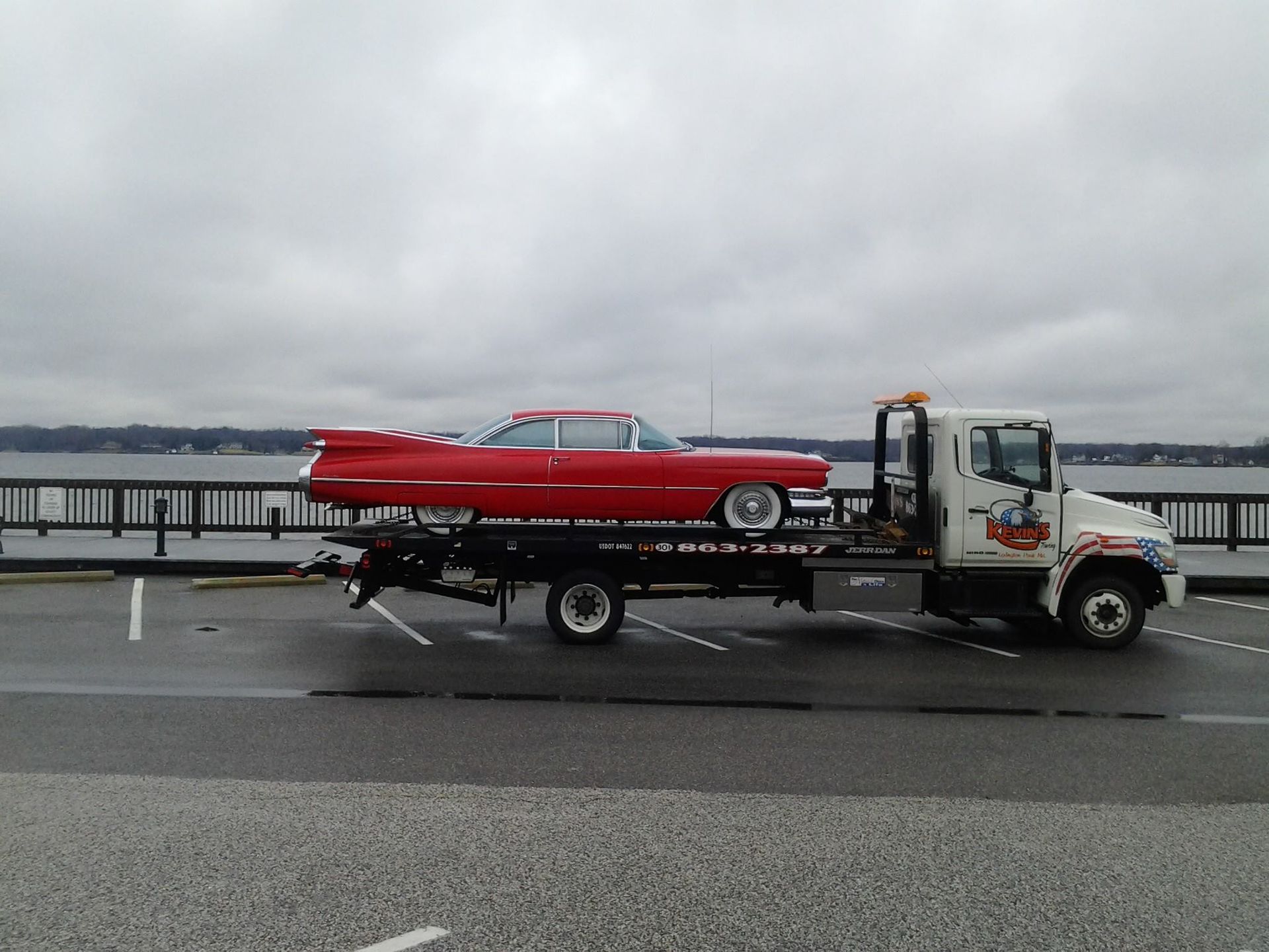 A red car is being towed by a tow truck
