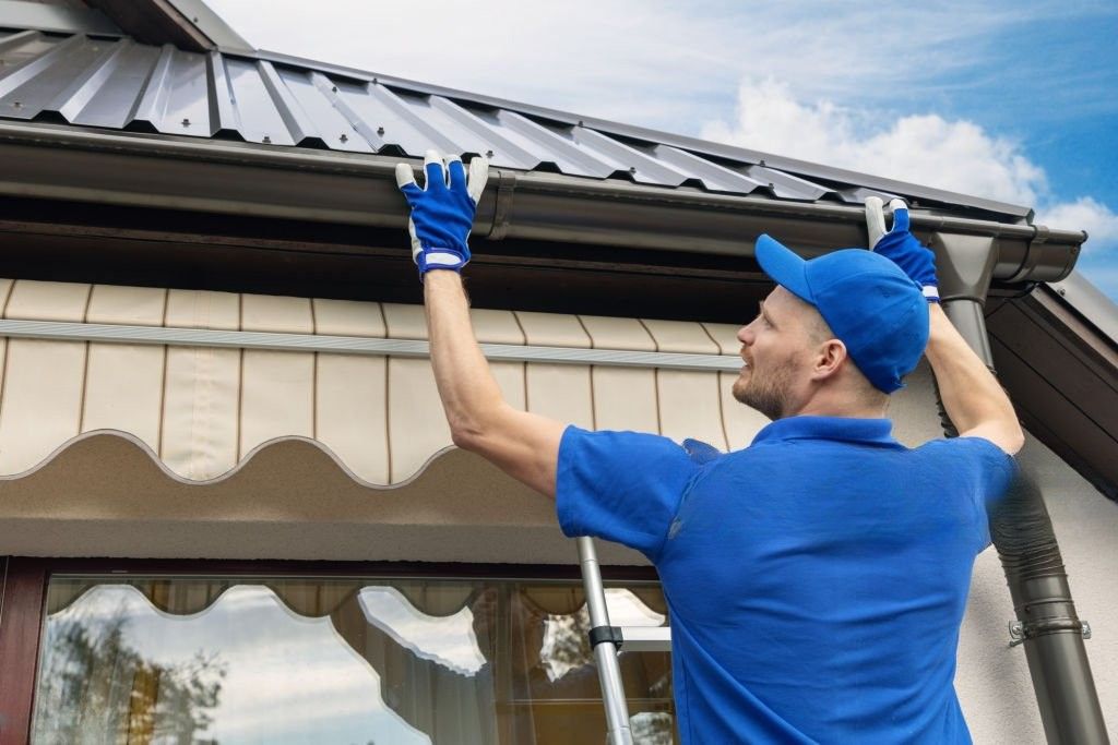 Technician cleaning house gutters to prepare for storm season in Texas