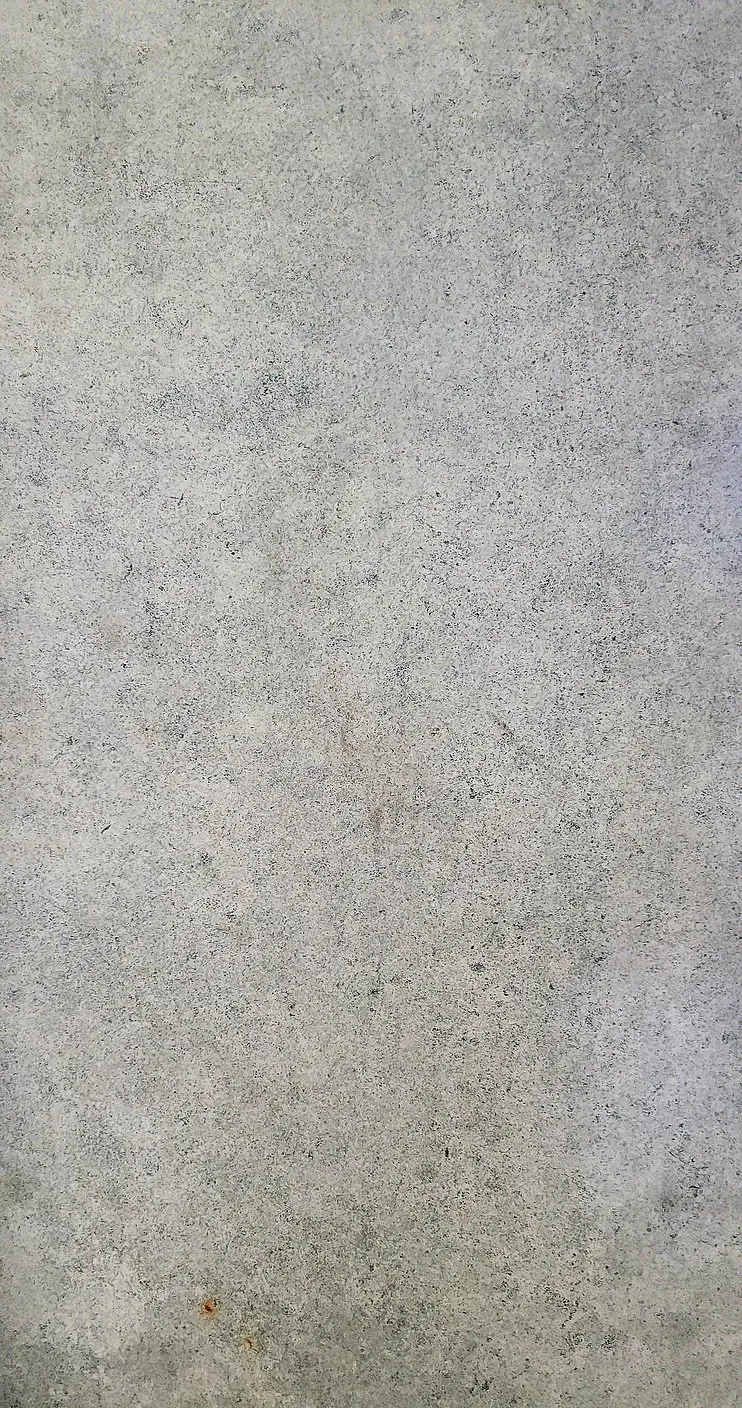 Close-up of a light gray speckled concrete wall with a few small stains
