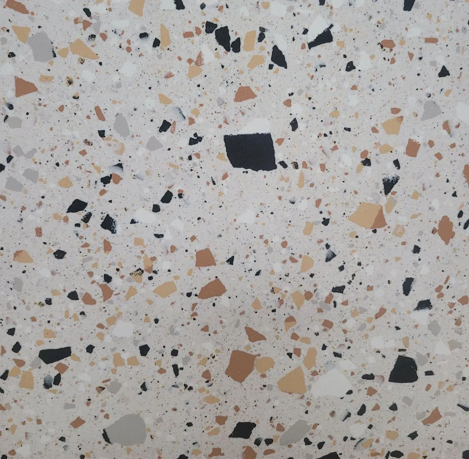 Close-up of white terrazzo flooring with scattered black, tan, and gray stone chips.