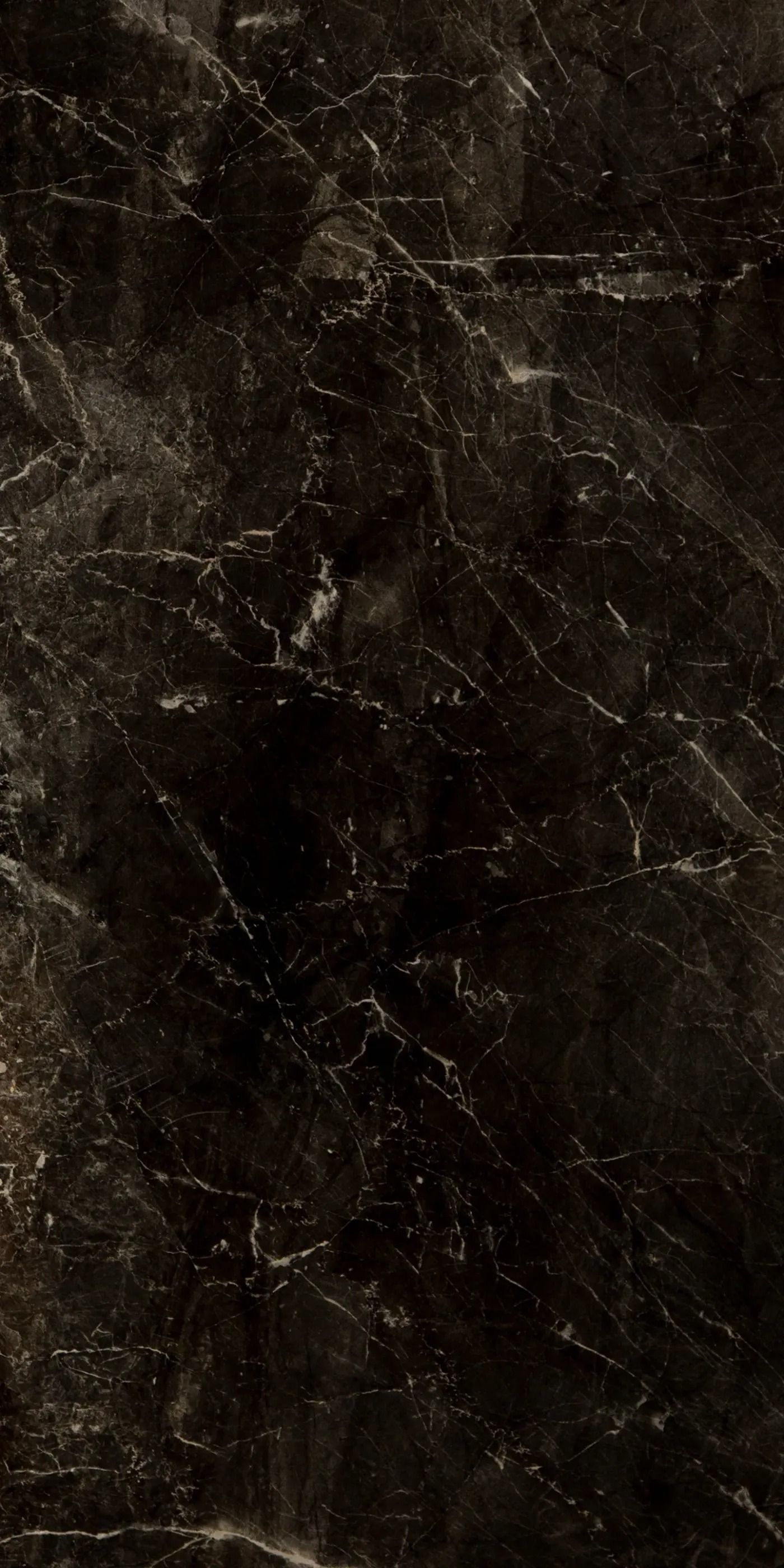 Dark, scratched black surface with subtle brown tones and wear marks