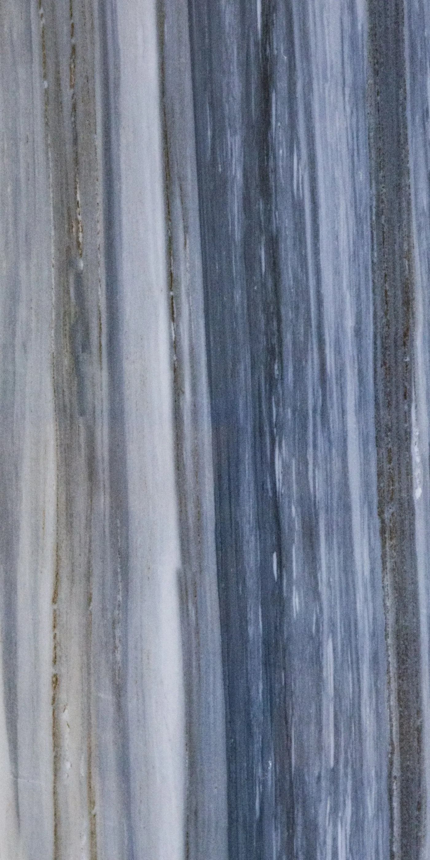 Abstract vertical gray, blue, and white streaks resembling painted wood grain or fabric texture.