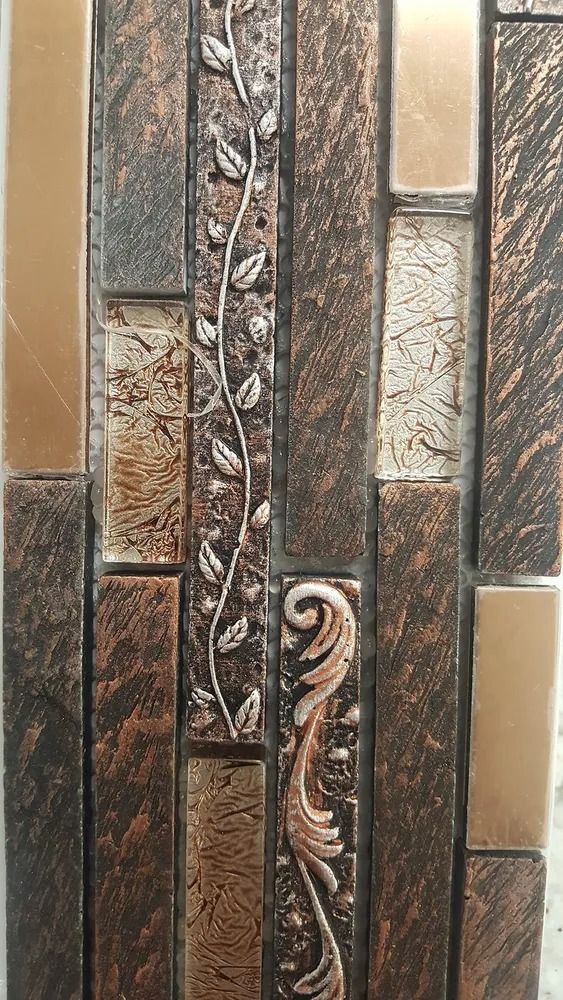Decorative brown and beige tiled wall with a vertical carved floral accent strip