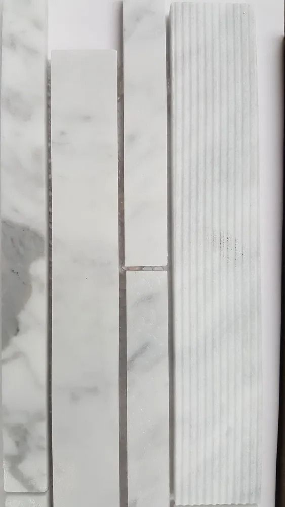 Close-up of white rectangular tiles or panels with thin gray seams and vertical grooves.