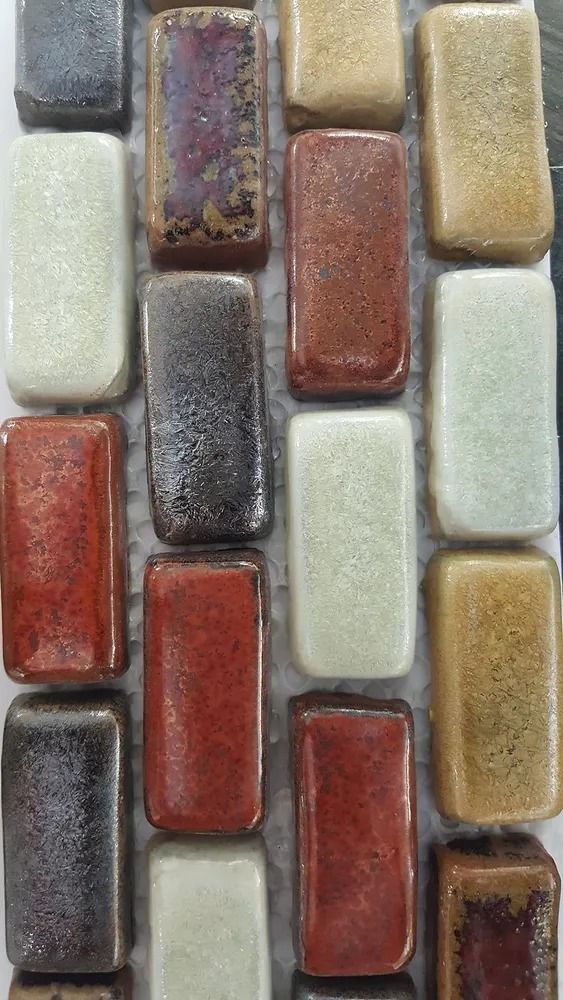 Close-up of multicolored rectangular mosaic tiles in cream, red, gray, gold, and purple tones