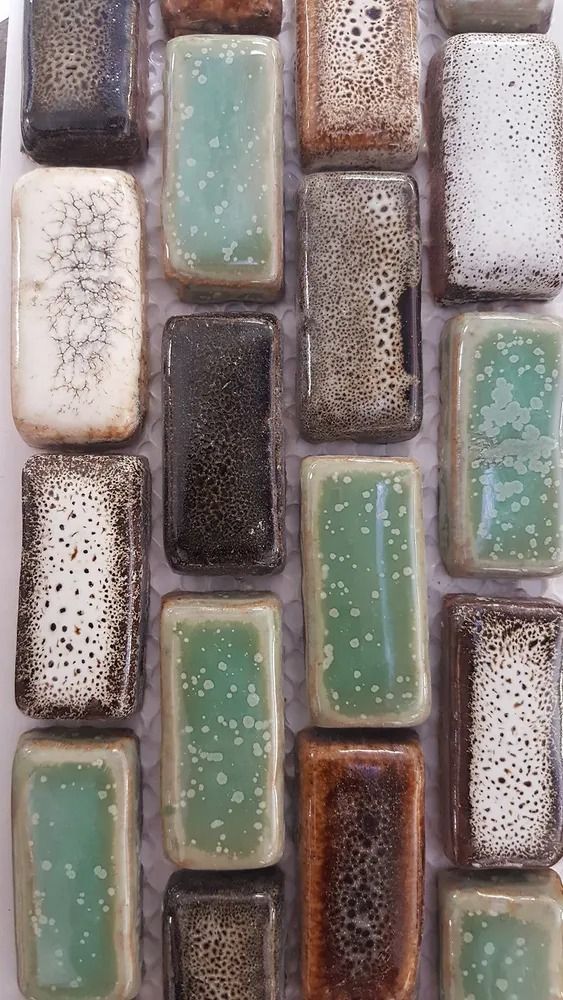 Close-up of textured mosaic tiles in muted green, gray, white, and brown tones.