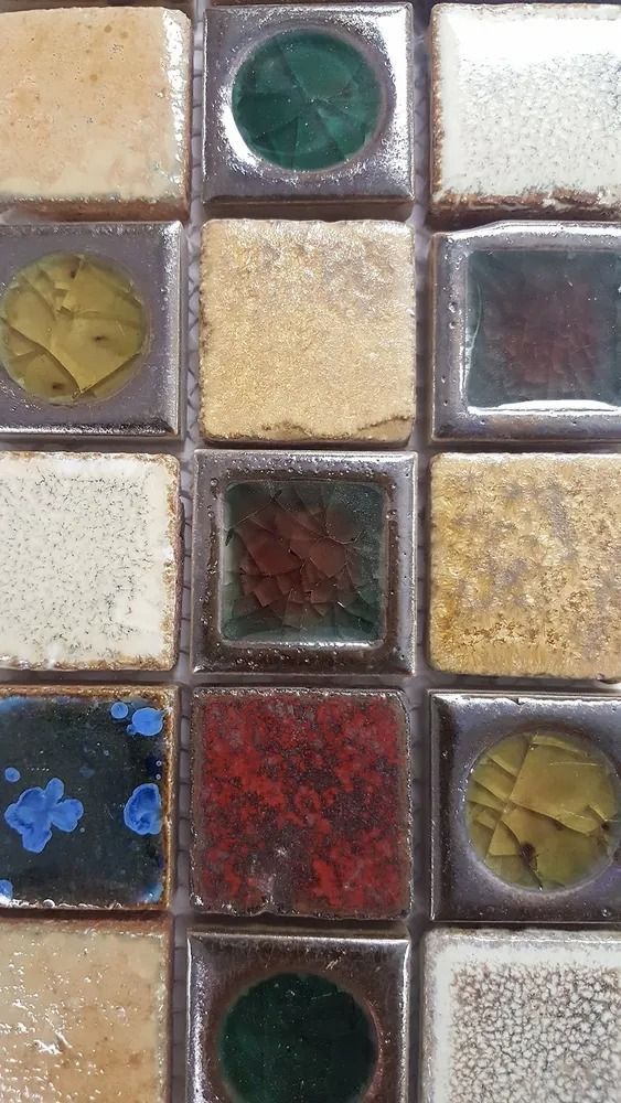 Close-up of colorful mosaic tiles with textured square and circular pieces in green, gold, red, blue, and white.