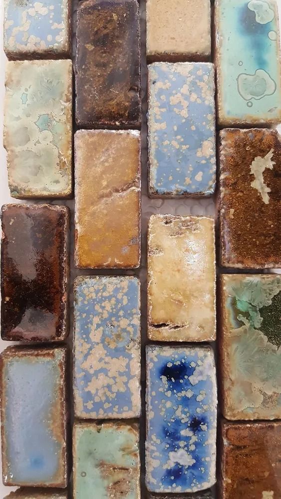 Vertical mosaic of weathered rectangular tiles in blue, tan, brown, and green tones