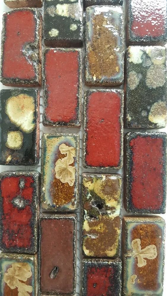 Abstract mosaic of red, brown, and cream rectangular tiles with glossy, textured surfaces