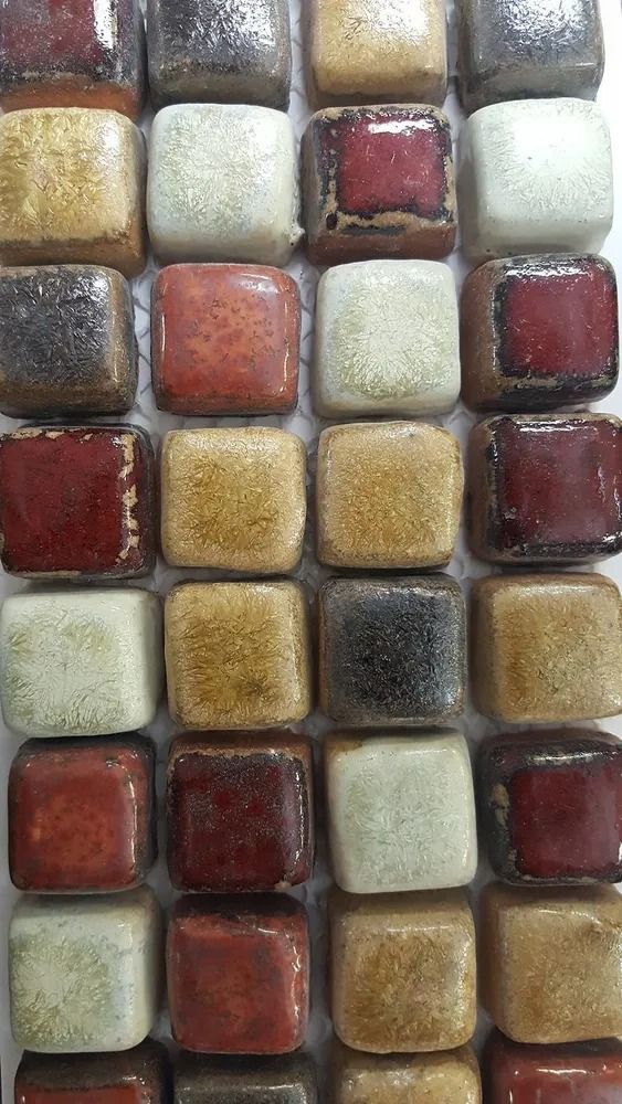 Close-up of colorful square mosaic tiles in red, gold, cream, and gray tones