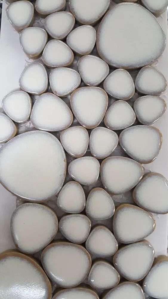 White and gray polished pebbles tightly packed against a light background.